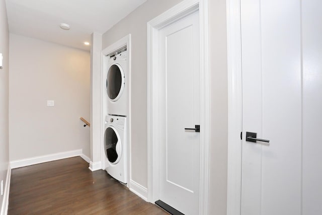 clothes washing area featuring laundry area, baseboards, dark wood-type flooring, and stacked washer / drying machine