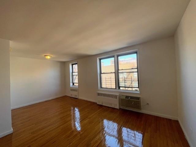 spare room featuring baseboards, radiator heating unit, and wood finished floors