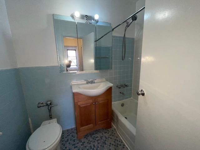 bathroom featuring tile walls, toilet, wainscoting, tub / shower combination, and vanity