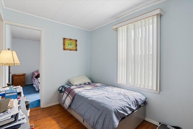 bedroom with crown molding, baseboards, and wood finished floors