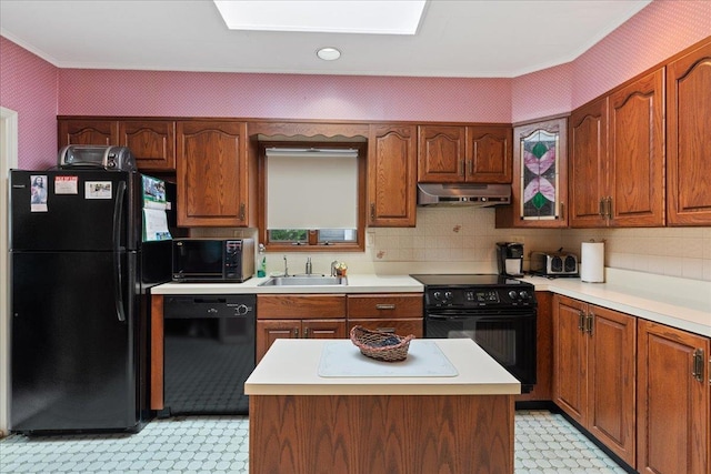 kitchen with black appliances, under cabinet range hood, light countertops, and a sink