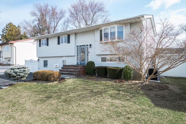 bi-level home featuring fence and a front lawn