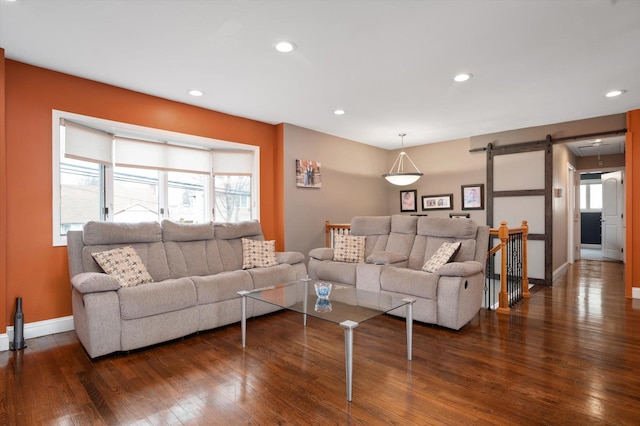 living area with a barn door, dark wood finished floors, and recessed lighting