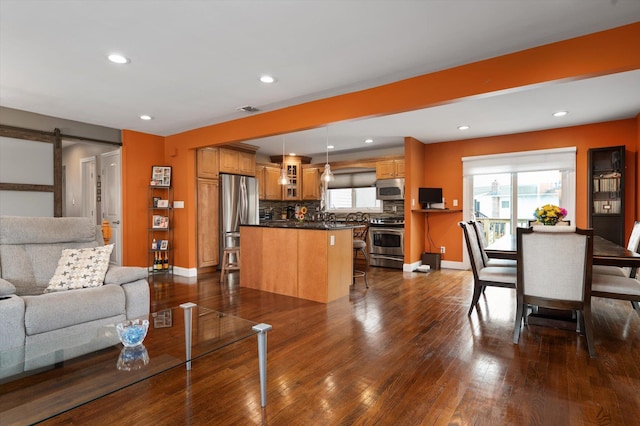 living area featuring a healthy amount of sunlight, dark wood-style floors, a barn door, and visible vents