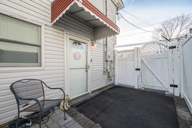 property entrance with a gate, a patio area, and fence