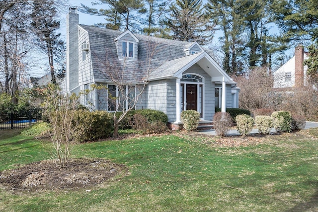 view of front of property featuring a shingled roof, a chimney, a gambrel roof, and a front yard