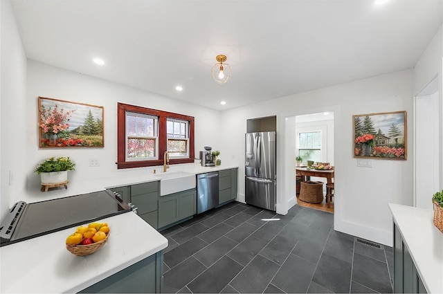 kitchen featuring appliances with stainless steel finishes, plenty of natural light, light countertops, and a sink