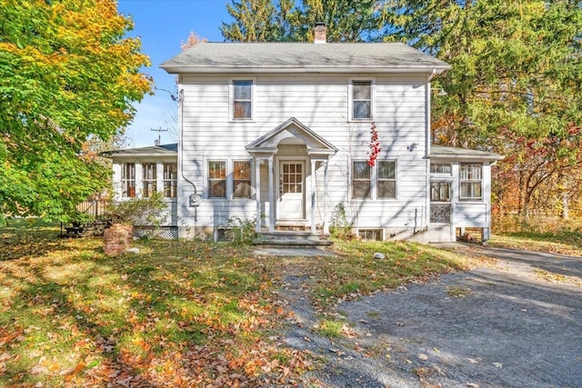 colonial house featuring a sunroom and a chimney