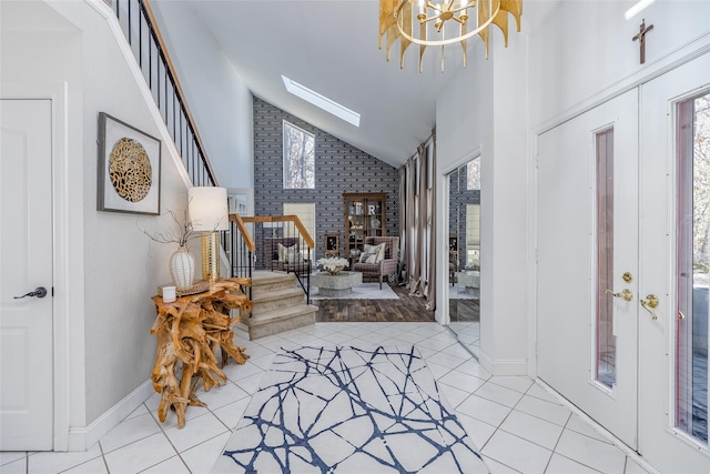 entrance foyer with a skylight, stairway, tile patterned flooring, french doors, and high vaulted ceiling