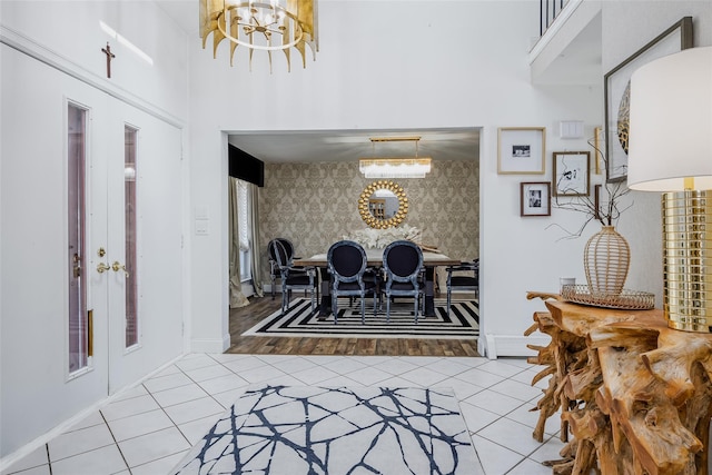 entrance foyer featuring wallpapered walls, baseboards, a notable chandelier, and tile patterned floors