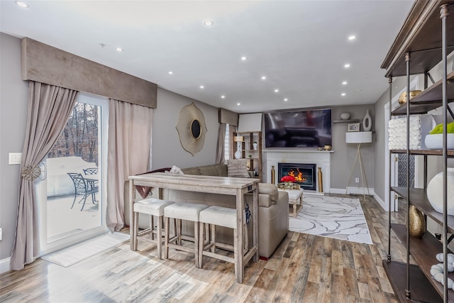 living room with recessed lighting, baseboards, wood finished floors, and a glass covered fireplace