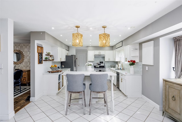 kitchen featuring under cabinet range hood, stainless steel appliances, a sink, a kitchen breakfast bar, and open shelves