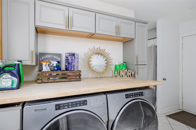 clothes washing area with cabinet space, washer and clothes dryer, and light tile patterned floors