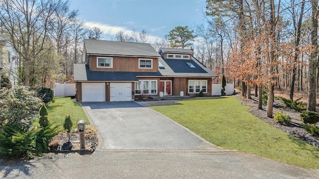 view of front of property with an attached garage, aphalt driveway, a front yard, and fence