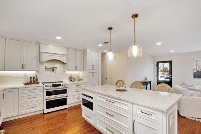 kitchen featuring open floor plan, range with two ovens, light wood-type flooring, and custom range hood