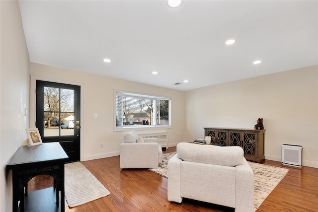 living area with baseboards, radiator heating unit, wood finished floors, and recessed lighting