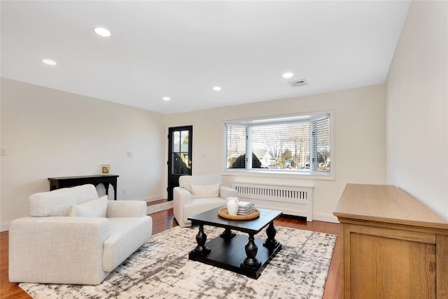 living area featuring recessed lighting, wood finished floors, visible vents, and radiator