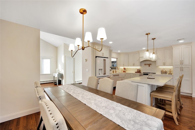 dining room featuring a baseboard heating unit, dark wood finished floors, visible vents, and baseboards