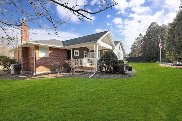 exterior space featuring brick siding, a chimney, central air condition unit, covered porch, and a lawn