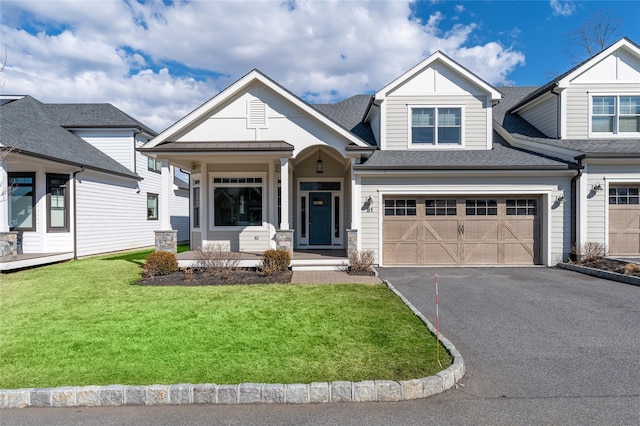 view of front of house featuring a shingled roof, a front yard, driveway, and an attached garage