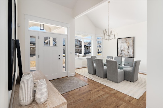 entrance foyer with a chandelier, vaulted ceiling, baseboards, and wood finished floors