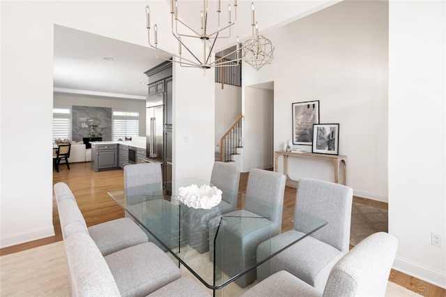 dining space featuring a chandelier, light wood-style floors, stairway, and baseboards