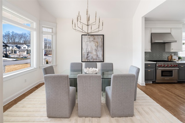 dining space featuring a chandelier, light wood-style flooring, and baseboards