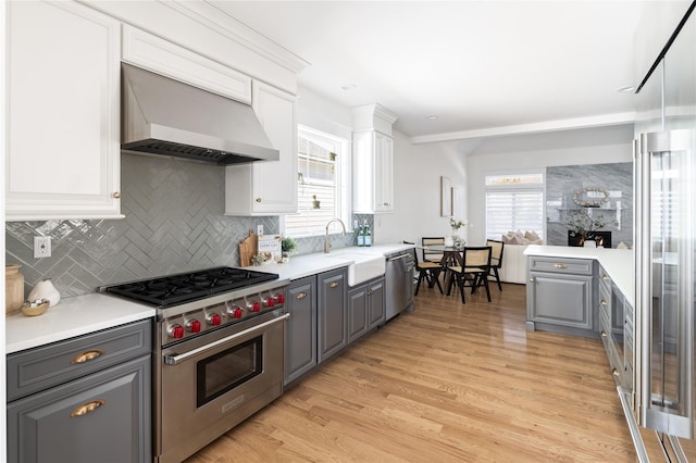 kitchen featuring wall chimney exhaust hood, appliances with stainless steel finishes, and gray cabinets