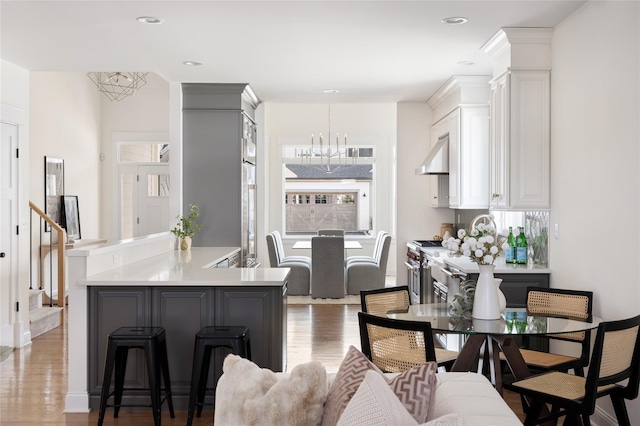 kitchen with light wood-type flooring, light countertops, white cabinetry, and under cabinet range hood