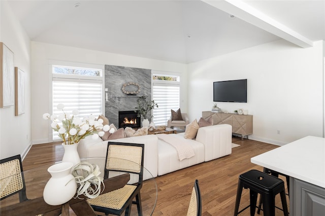 living area with high vaulted ceiling, a fireplace, wood finished floors, and baseboards