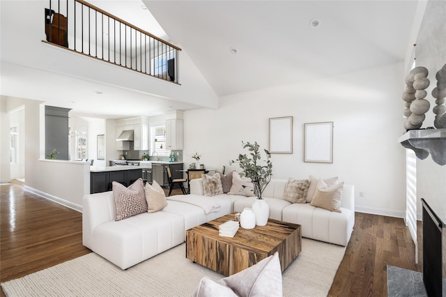 living room with high vaulted ceiling, a fireplace with flush hearth, baseboards, and wood finished floors