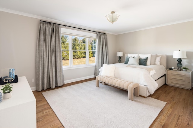 bedroom with ornamental molding, light wood-style flooring, and baseboards