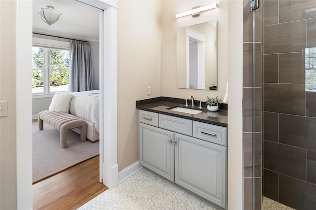 full bath featuring vanity, wood finished floors, tiled shower, and ensuite bathroom