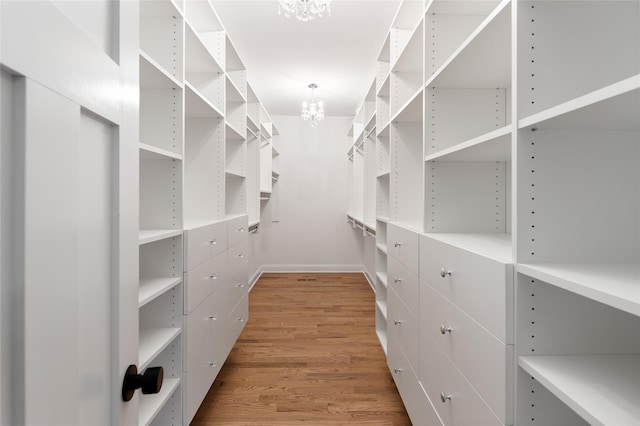 walk in closet featuring a chandelier and light wood-style floors