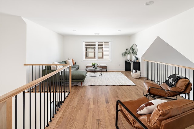 sitting room with light wood-style floors, baseboards, and an upstairs landing