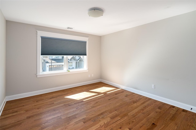 empty room with visible vents, baseboards, and wood finished floors