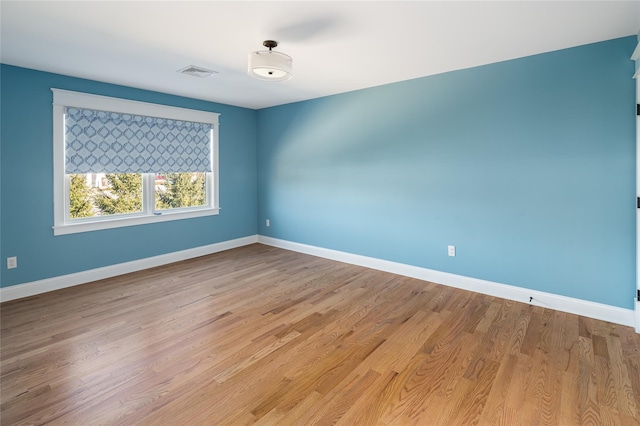 unfurnished room featuring light wood finished floors, baseboards, and visible vents