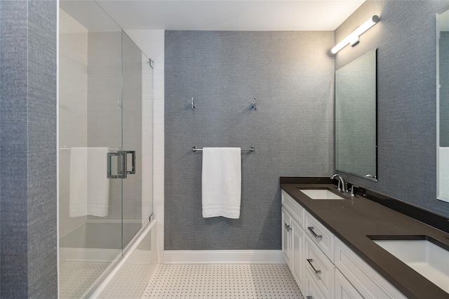 full bathroom with double vanity, shower / bath combination with glass door, baseboards, and a sink