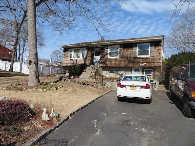 view of front facade featuring aphalt driveway and fence