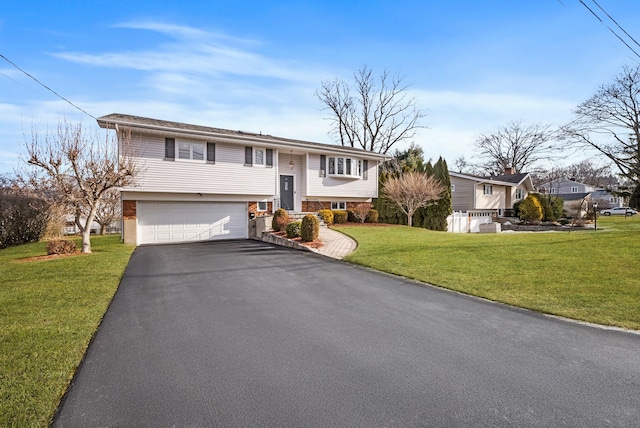 raised ranch featuring aphalt driveway, a front lawn, and an attached garage