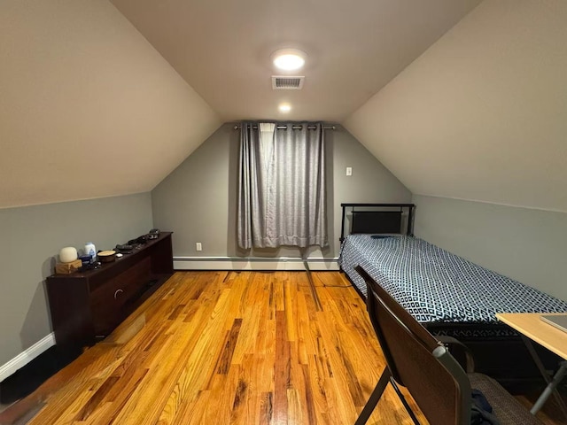 bedroom featuring a baseboard radiator, wood finished floors, visible vents, baseboards, and vaulted ceiling