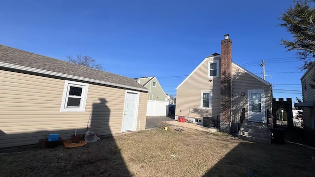 exterior space with a chimney, fence, and roof with shingles