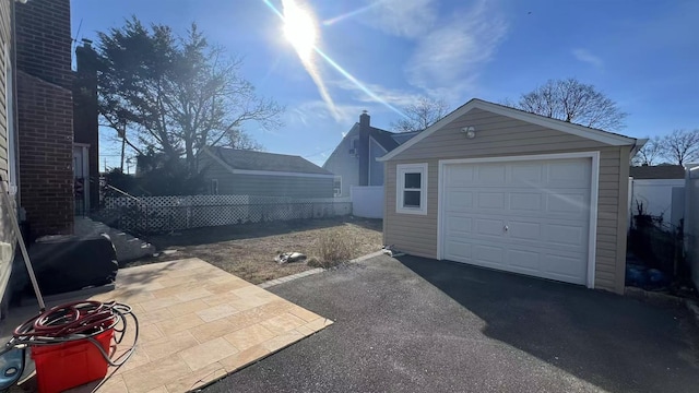 detached garage with aphalt driveway and fence