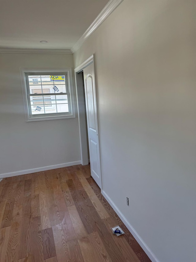 spare room with crown molding, baseboards, and wood finished floors