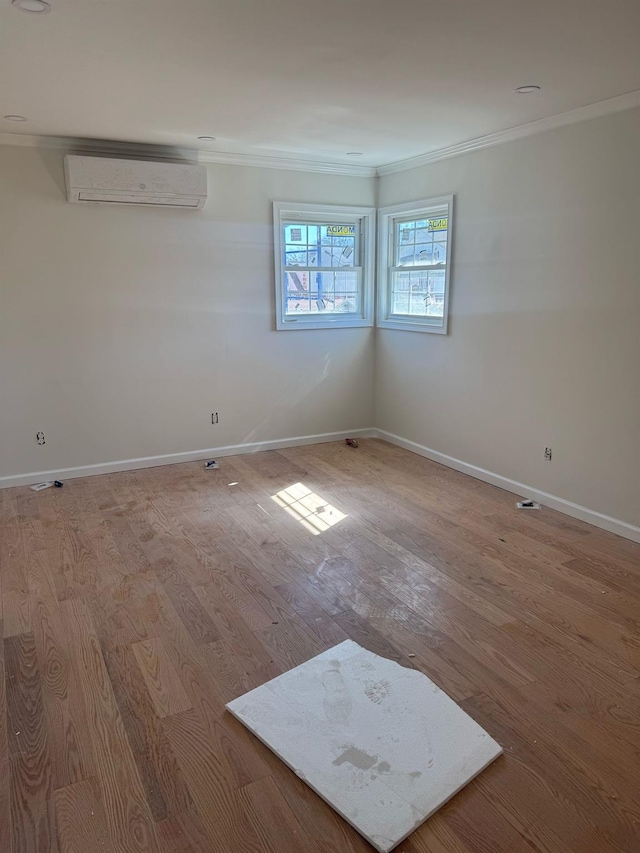 empty room with baseboards, an AC wall unit, wood finished floors, and crown molding