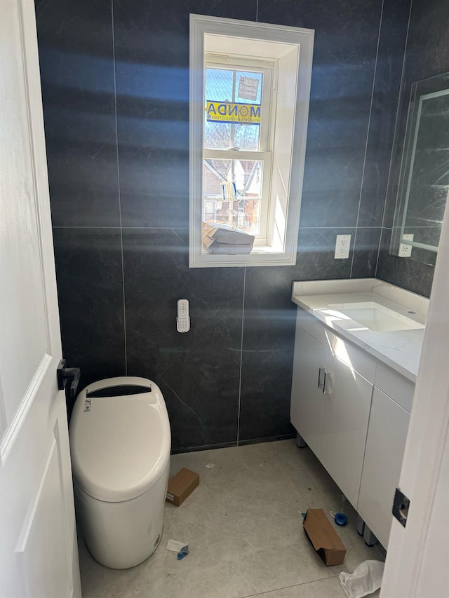 half bath featuring toilet, vanity, and tile walls