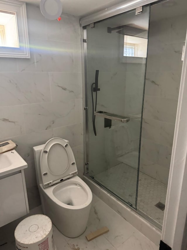 bathroom featuring toilet, marble finish floor, a stall shower, and vanity