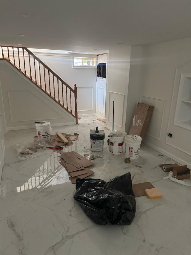 interior space featuring marble finish floor, stairs, and a decorative wall