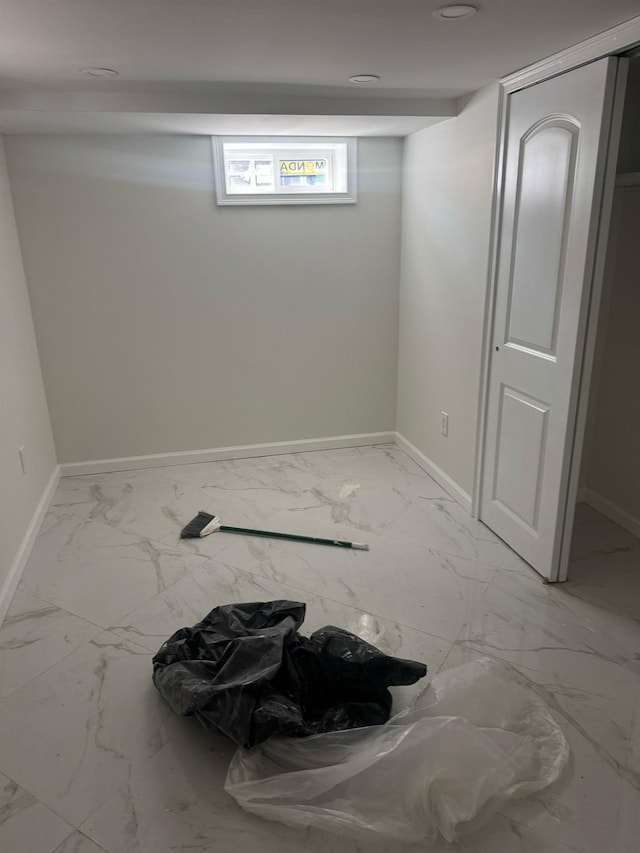 basement featuring marble finish floor and baseboards