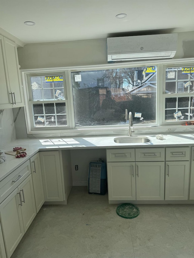 kitchen with decorative backsplash, light countertops, a wall mounted AC, a sink, and light tile patterned flooring